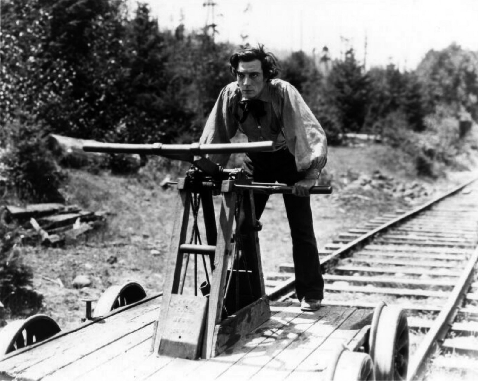 The General — Buster Keaton bent over a two-man railroad handcar on the tracks